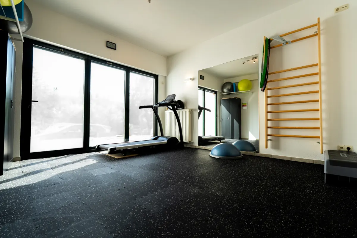 Sonniger Trainingsraum mit Laufband, Sprossenwand und Balancebällen